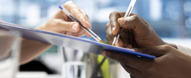 Close-up of two people signing real estate or mortgage documents on a clipboard during a property appraisal meeting.